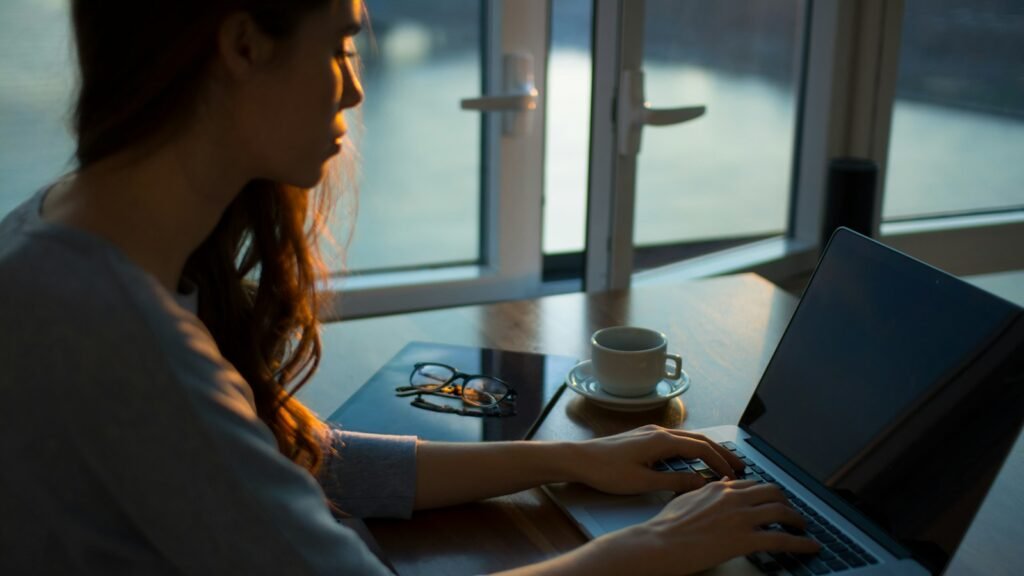 Woman working on a laptop at a table by the window