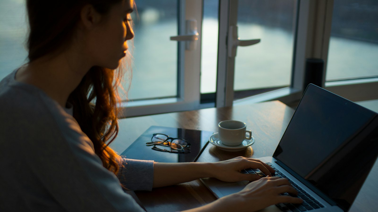 Woman working on a laptop at a table by the window