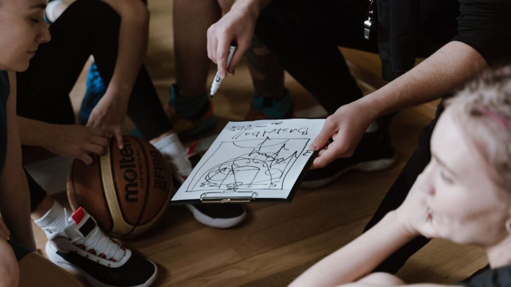 Coach drawing up a play on paper with a basketball nearby