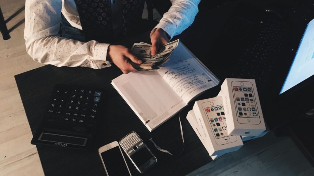 Person counting cash next to a calculator and a notebook