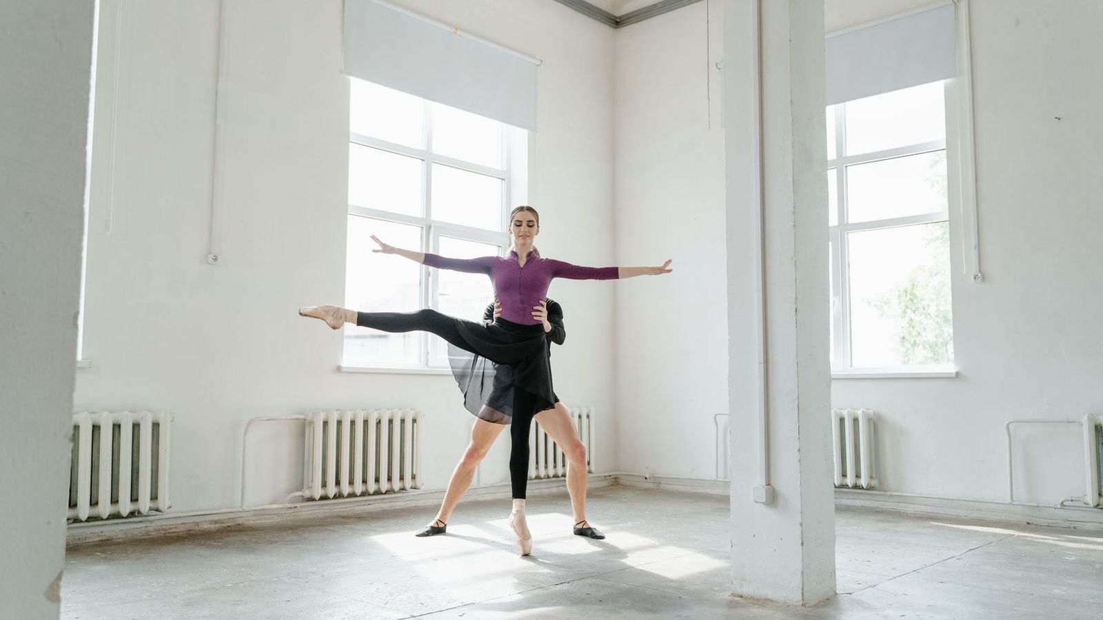 Dancer stretching in a bright, empty studio
