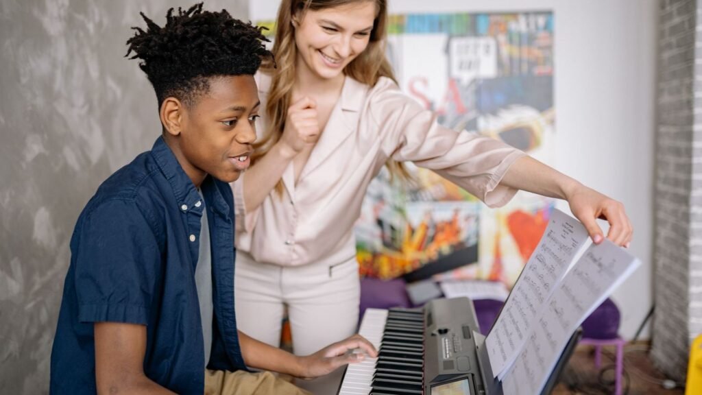 Music teacher guiding a boy playing a keyboard