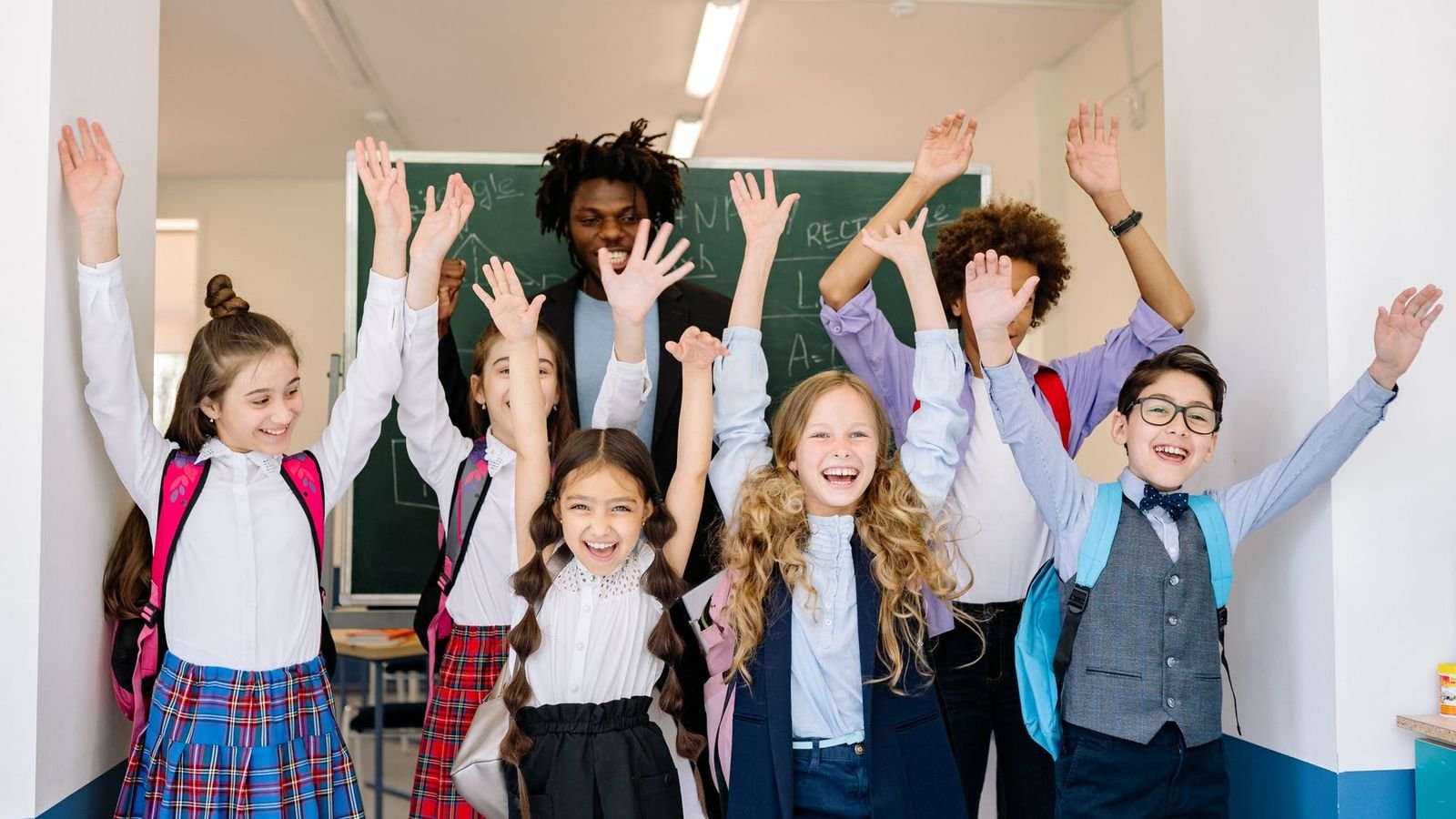 Excited school children cheering with their arms in the air