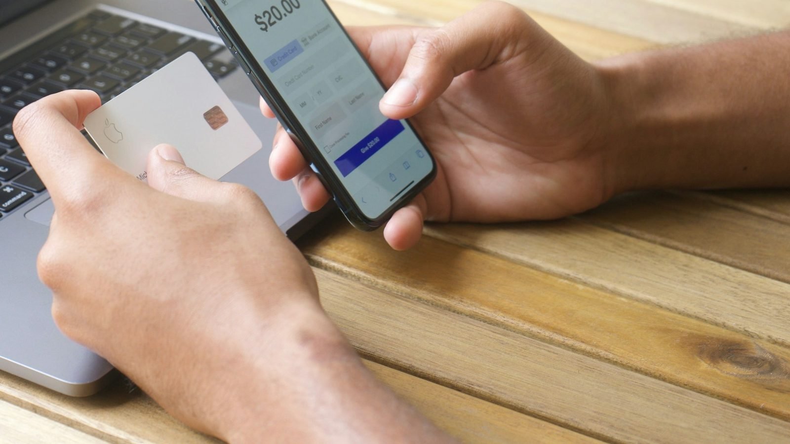 Person paying with a card on a phone next to a laptop