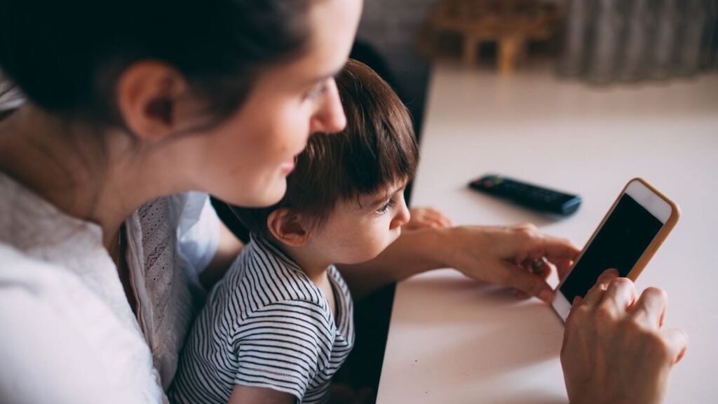 Parent reading a message on her phone while sitting with her child