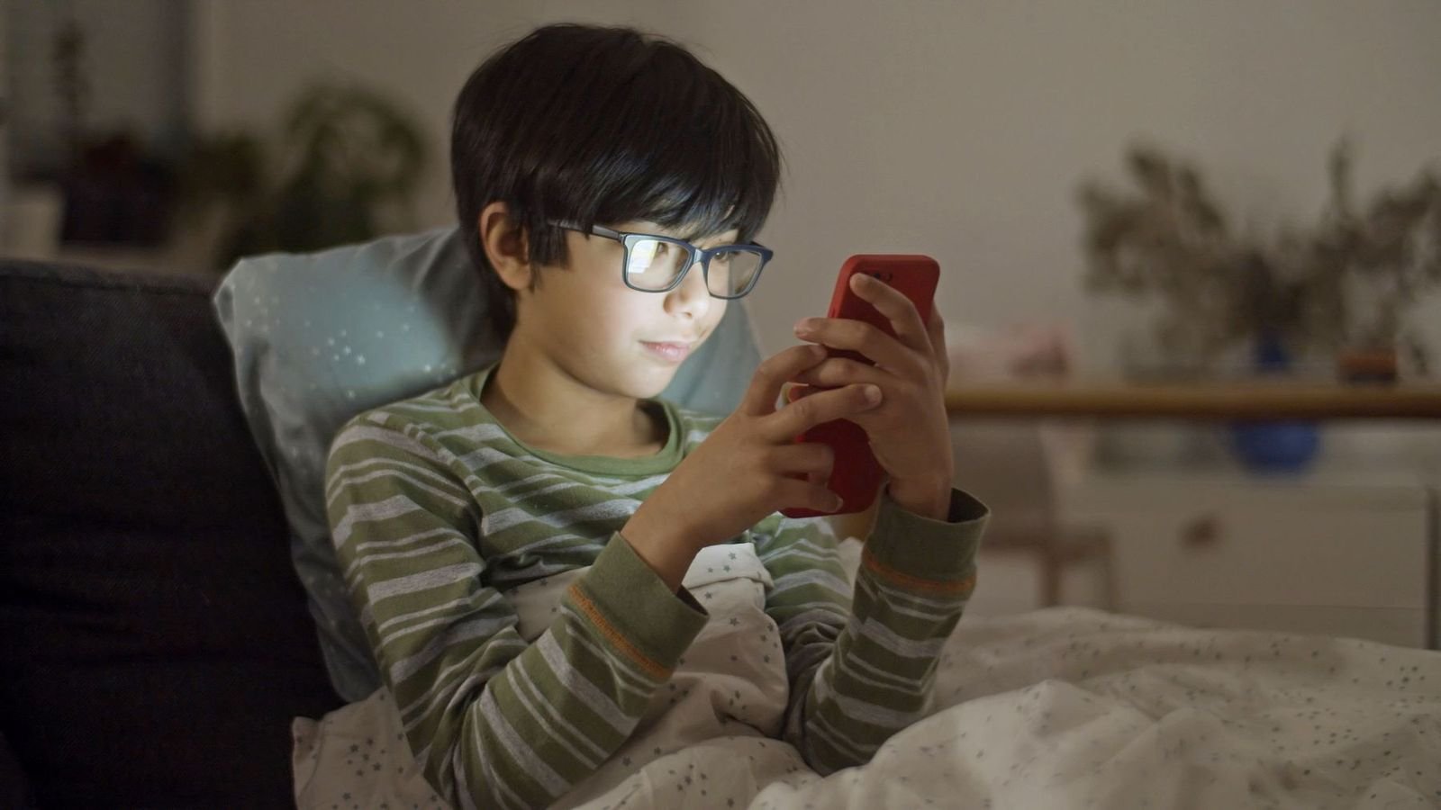 Child looking at a phone on a couch