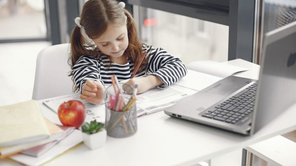 Girl working at a desk with notebooks and a laptop
