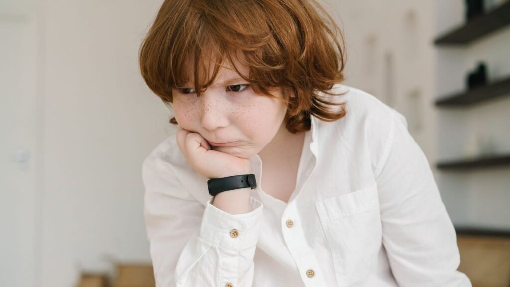 Young boy resting his chin on his hand, looking bored