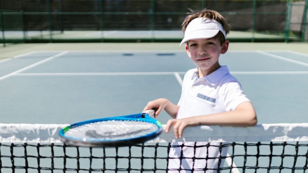 Smiling boy holding a tennis racquet at the net