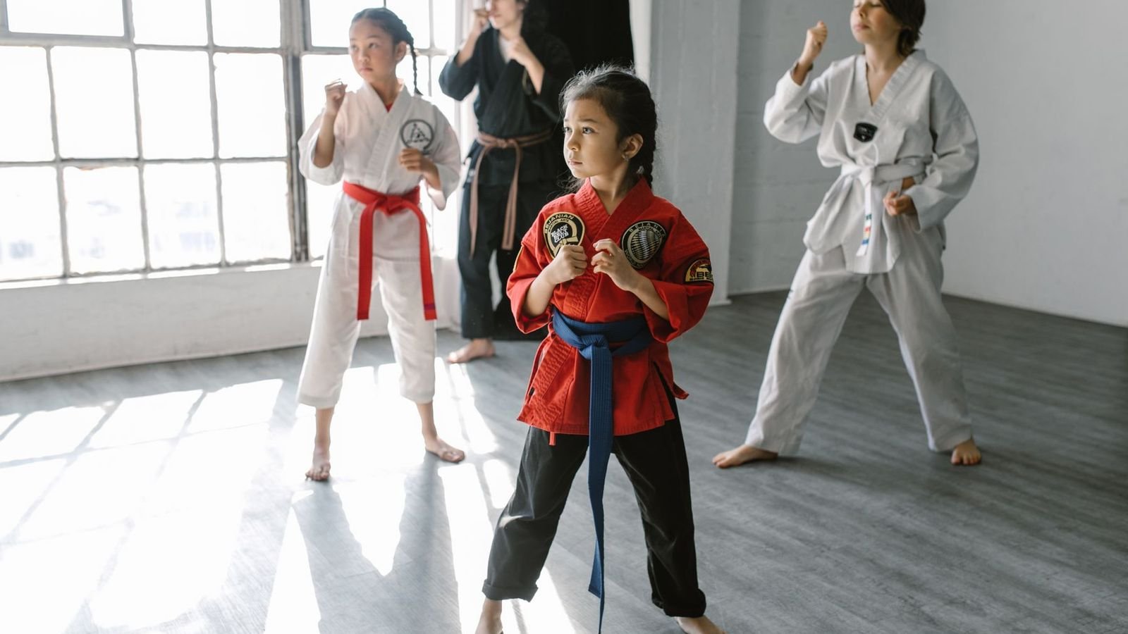 Young girl in a martial arts class practising a stance with classmates